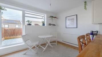 A bright room with a table and chairs, a radiator, and a window with a view of a building.