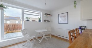 A bright room with a table and chairs, a radiator, and a window with a view of a building.