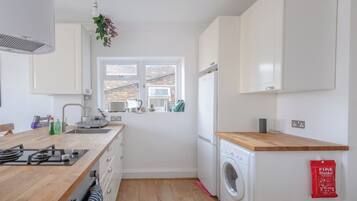 A compact kitchen with a sink, stove, and a window with a view of a brick building.