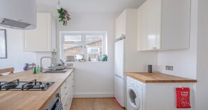 A compact kitchen with a sink, stove, and a window with a view of a brick building.