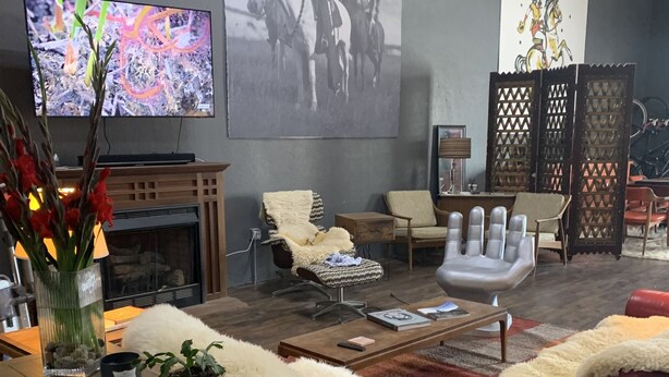 Een moderne woonkamer met een open haard, een grote flatscreen-tv en een wandkunstwerk.