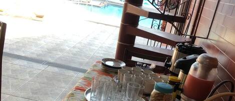 A table with a floral tablecloth, a cake, bread, and a basket of rolls.