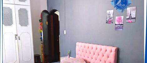 Quarto com cama de casal, guarda-roupa e parede decorada com quadros.
