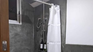 Un baño con ducha, inodoro y una pequeña ventana.