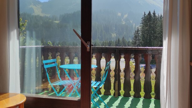 A room with a sliding glass door leading to a balcony with a view of mountains.