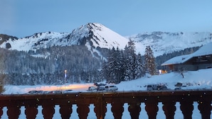 A snowy mountain landscape with a wooden building and parked cars.