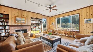 A cozy living room with a fireplace, leather sofas, a coffee table, and a bookshelf.
