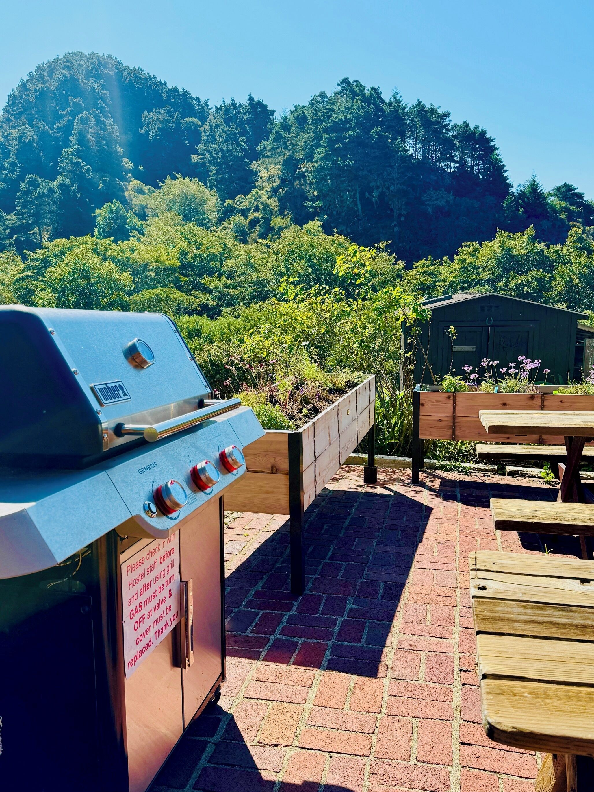 A barbecue grill with a sign instructing to check with staff before using.