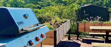 A barbecue grill with a sign instructing to check with staff before using.