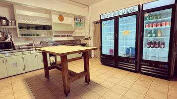 A kitchen with a wooden table, a clock, and two refrigerators labeled "Limantour Lodge".