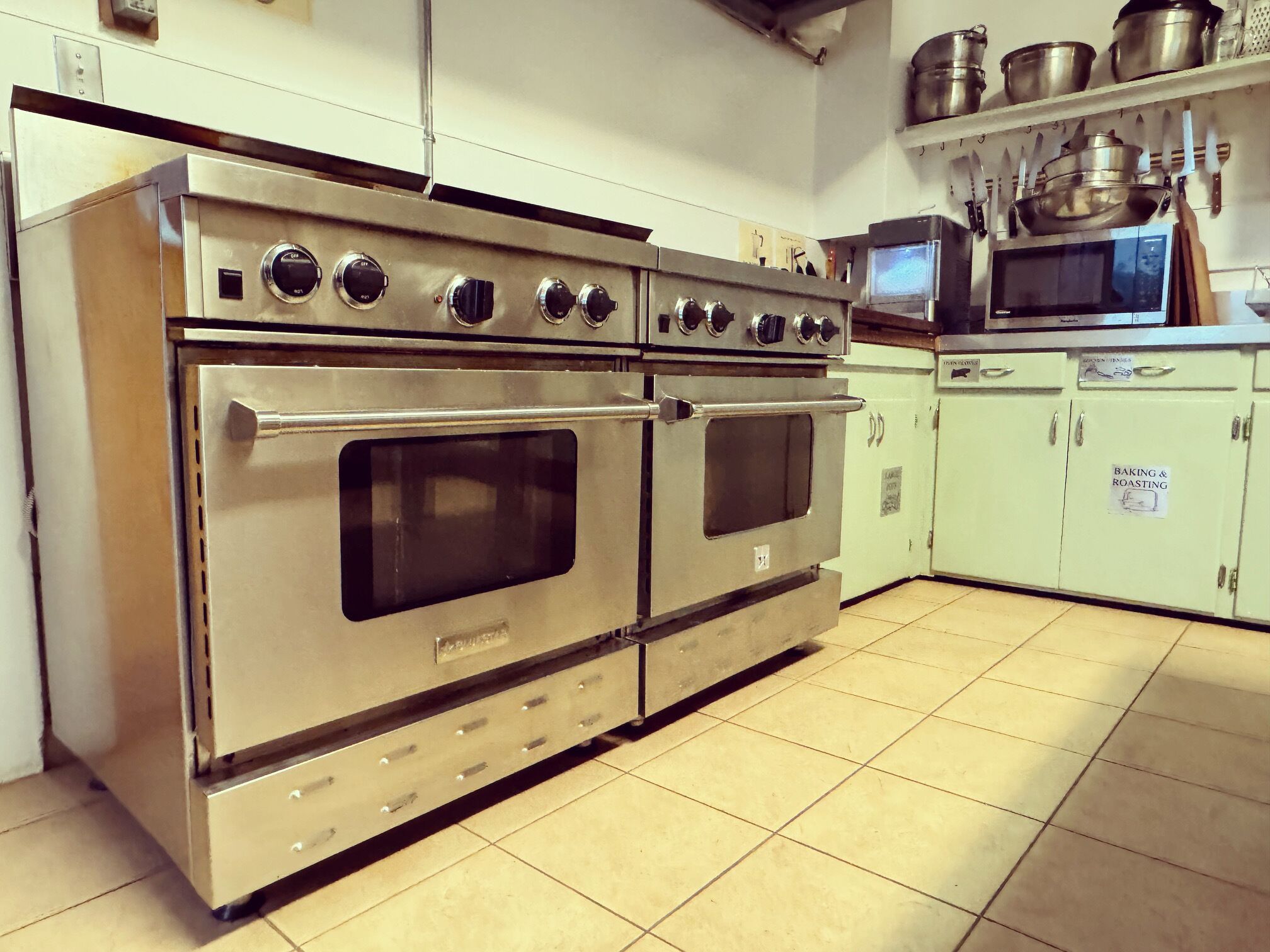 Una cocina de acero inoxidable con cuatro hornos y un microondas.