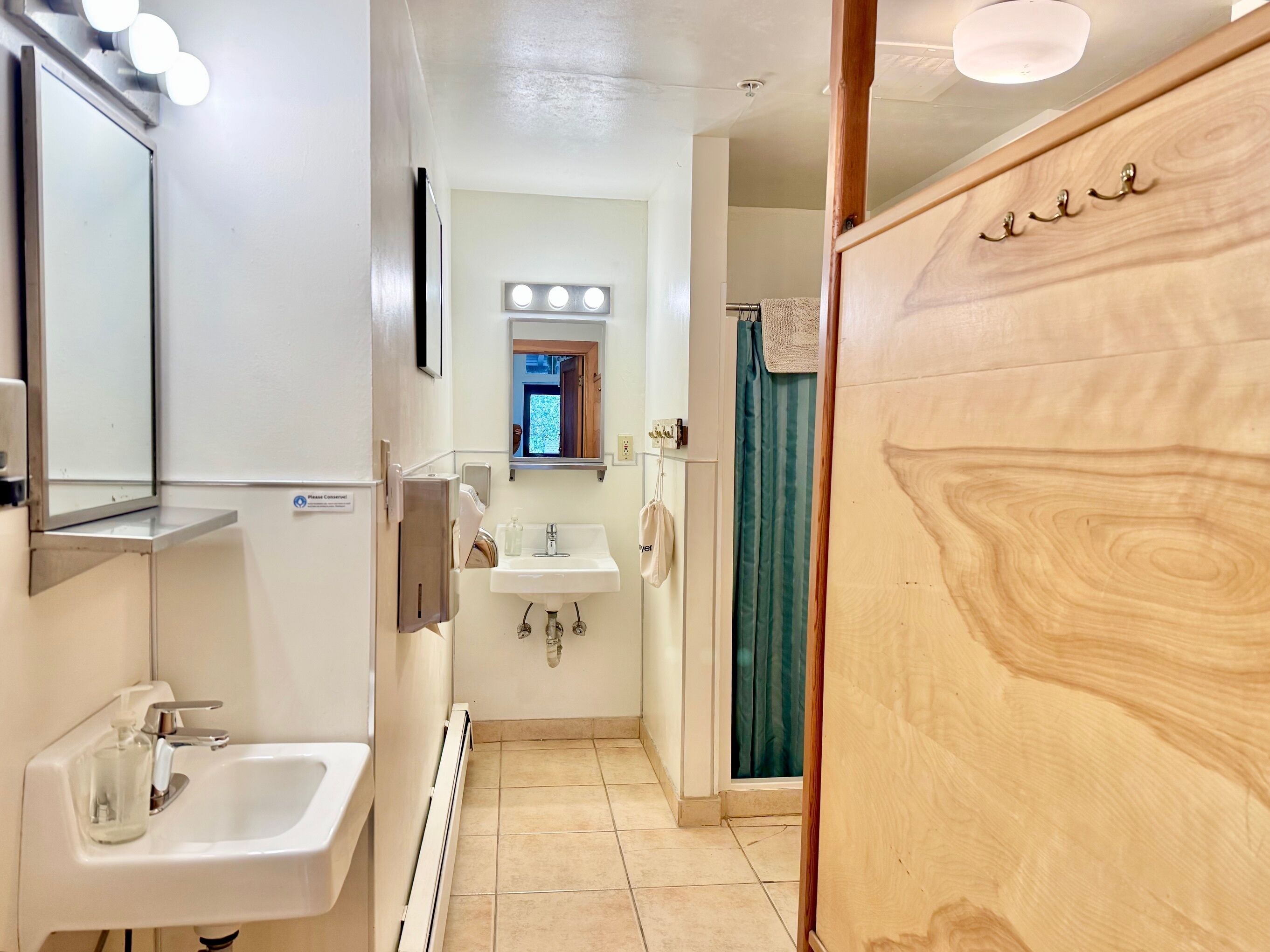 A bathroom with a sink, mirror, and vanity. There is a shower curtain and a towel rack.