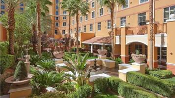 A courtyard with palm trees, a fountain, and a building with balconies.