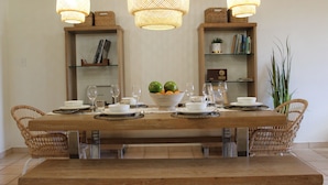 A dining table set with plates, bowls, and glasses, flanked by wicker chairs. - Seaside, Tennis, Pickleball, Golf, Pool (Humacao)