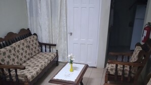 A living room with a sofa, two armchairs, a coffee table, and a door marked "Exit". - Hilltop View Guesthouse (Castries)
