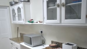 A kitchen with white cabinets, a microwave, a toaster, and a granite countertop. - Hilltop View Guesthouse (Castries)