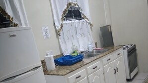 A compact kitchen with white cabinets, a built-in oven, and a gas stove. - Hilltop View Guesthouse (Castries)