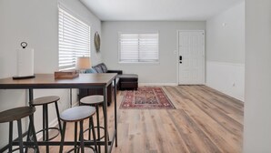 Eine moderne Küche mit Essbereich, ausgestattet mit einem Holztisch, Barhocker und einem gemusterten Teppich.