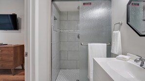 Ein modernes Badezimmer mit Dusche, Waschbecken und Spiegel.