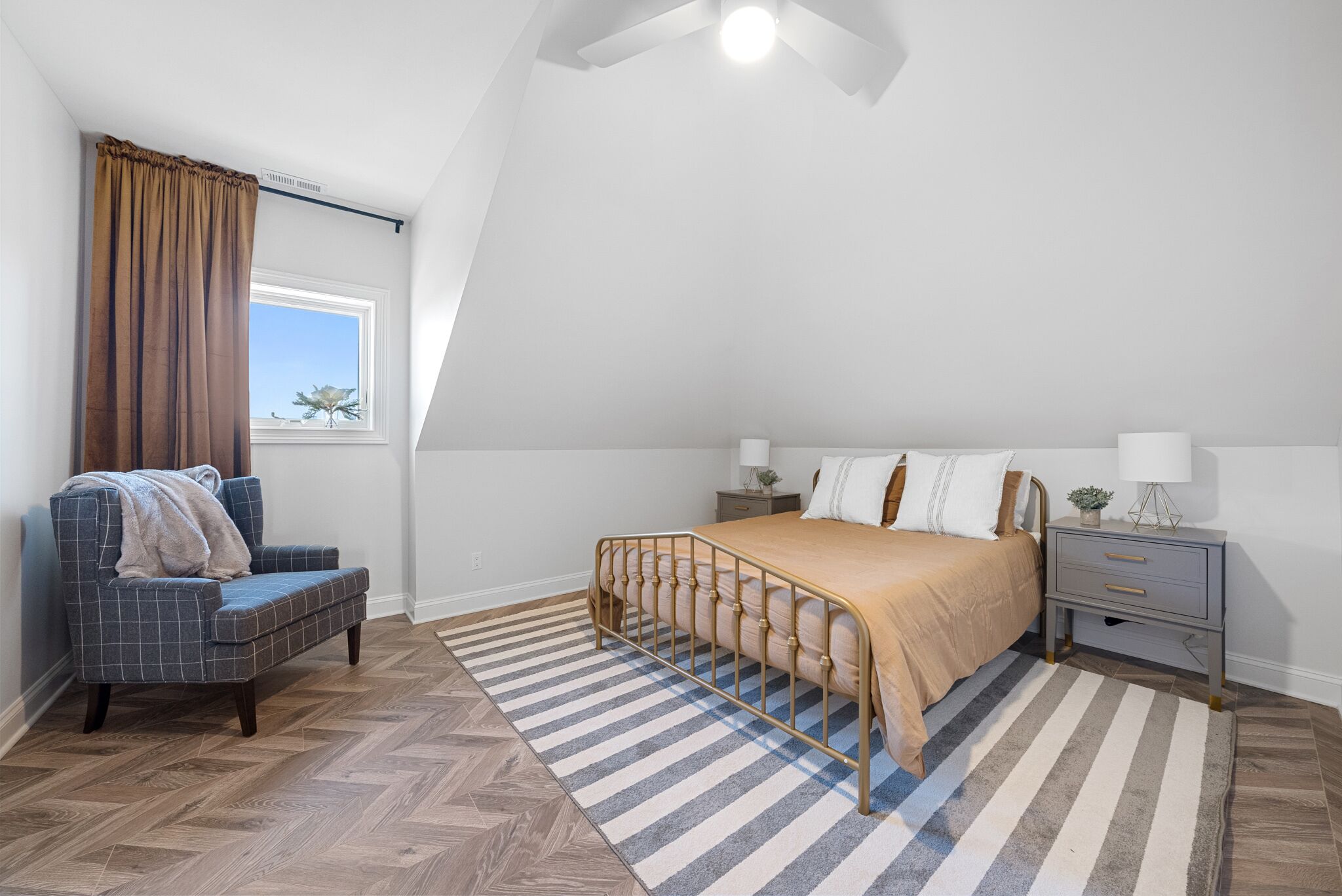 Een slaapkamer met een bed, een stoel, een nachtkastje en een raam met gordijnen.
