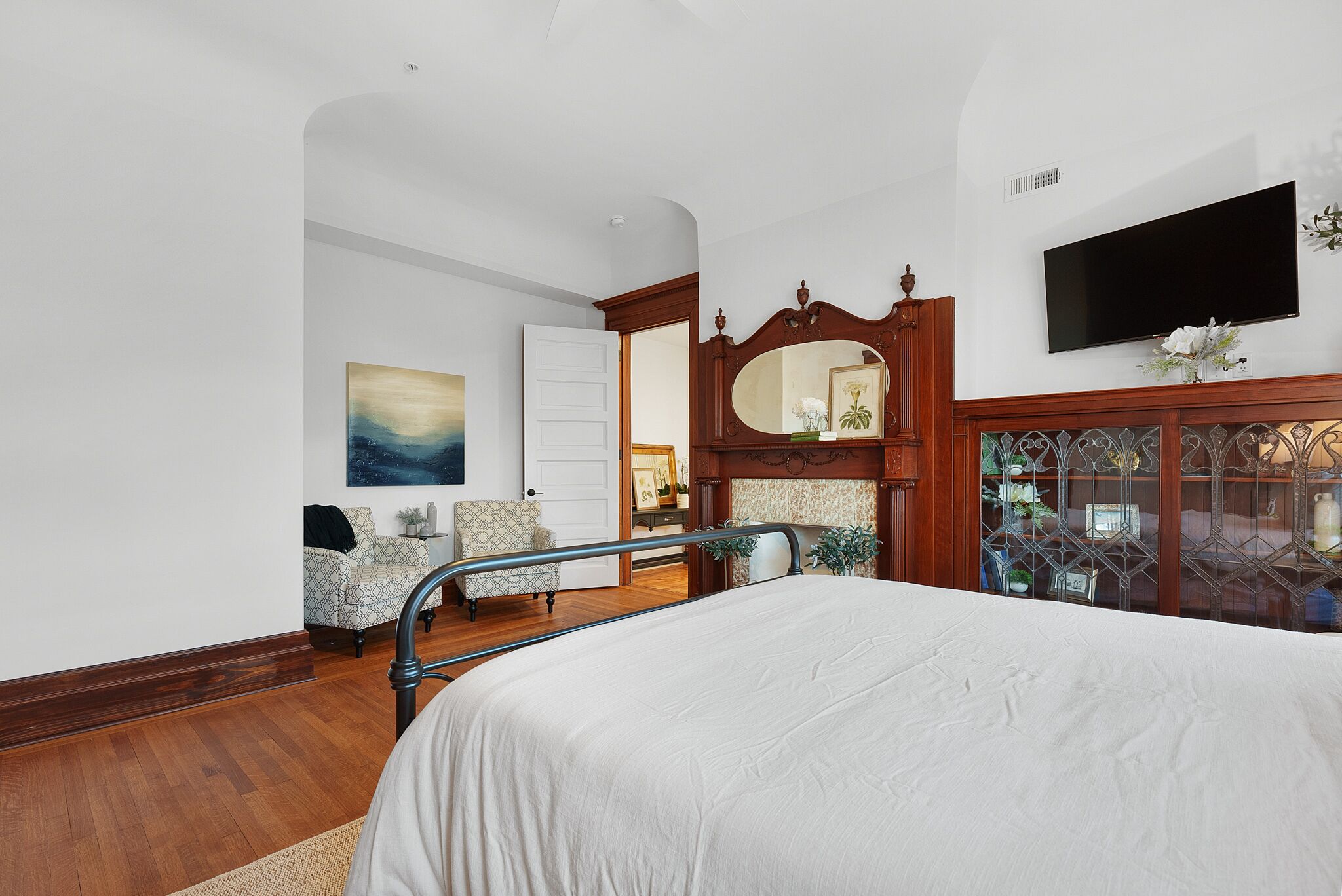 A bedroom with a bed, a TV, a mirror, and a chair.