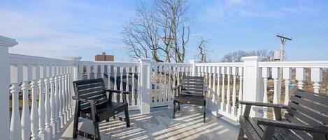A wooden deck with white railings and two wooden benches.