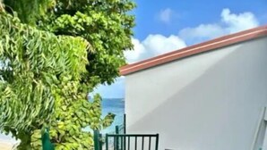 A wooden deck with a gate, a small seating area, and a view of the ocean. - Grand Case Beach (Grand Case)