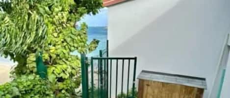 A wooden deck with a gate, a small seating area, and a view of the ocean.