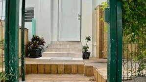 A wooden staircase leading to a white door, surrounded by greenery and potted plants. - Grand Case Beach (Grand Case)