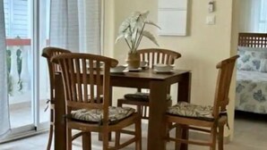 A dining area with a table and four wooden chairs, a potted plant, and a sliding glass door leading to an outdoor area. - Grand Case Beach (Grand Case)