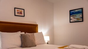 A hotel room with a bed, pillows, a nightstand with a lamp, and towels on the bed.