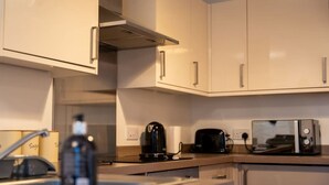 A kitchen with white cabinets, a coffee maker, a toaster, and a microwave.