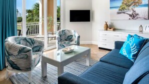 Un salon moderne avec un canapé, des fauteuils, une table basse et un téléviseur.