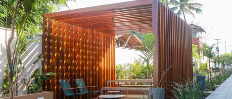 A modern outdoor seating area with wooden slats, a round table, and two chairs.