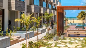 A modern hotel with multiple balconies, a pool area, and a view of the beach.