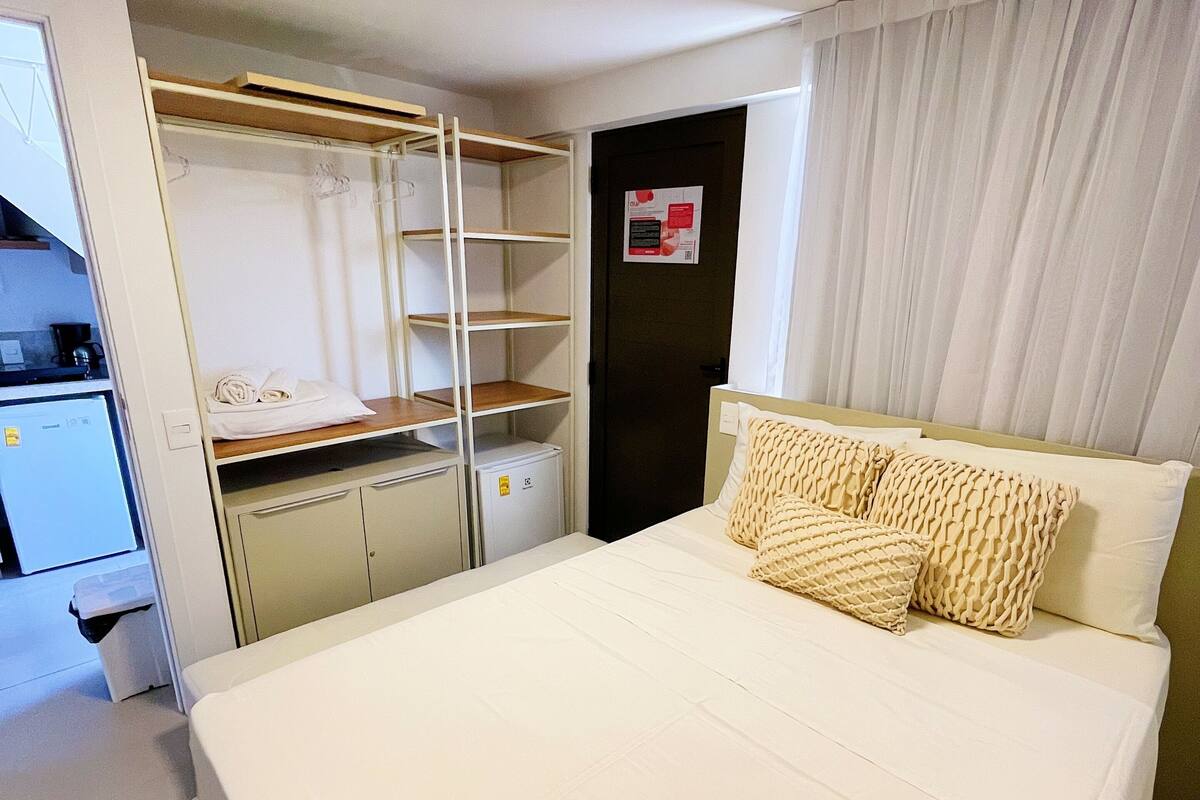 Habitación de hotel con cama, armario, escritorio y baño.