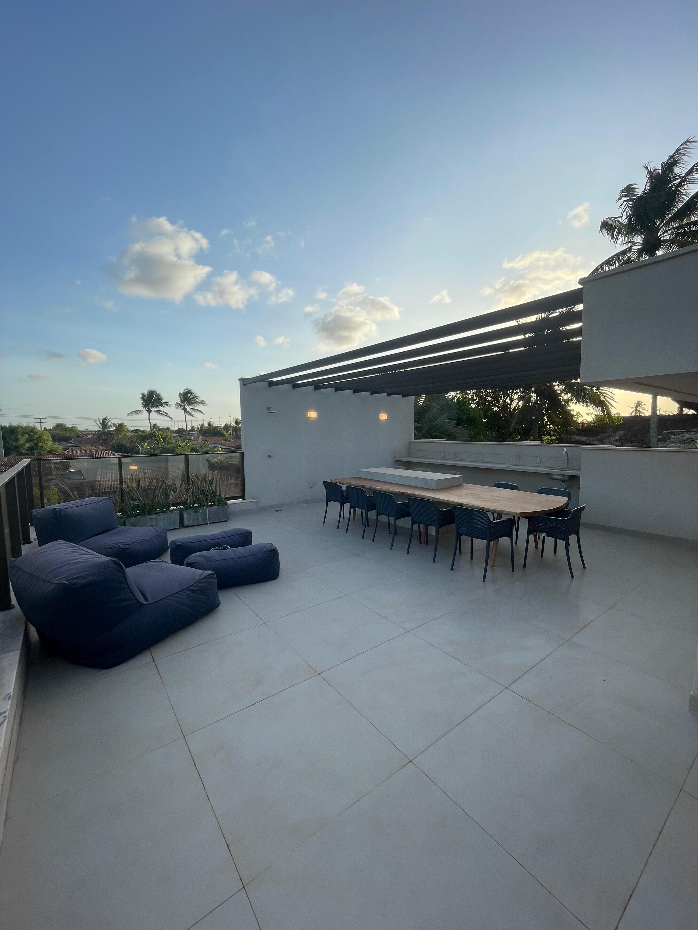A rooftop terrace with a dining area, seating, and a pergola.