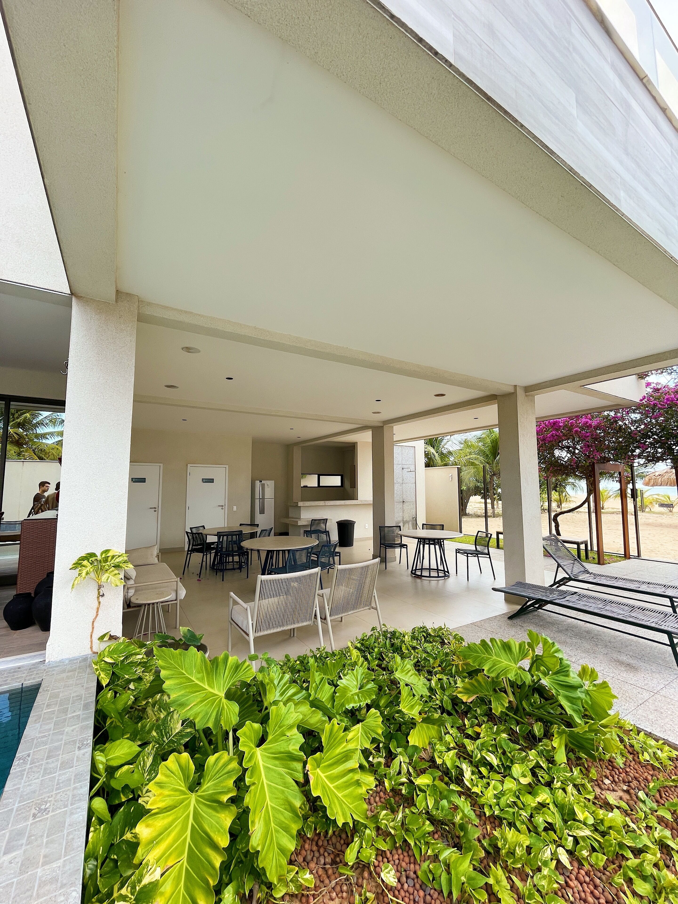 A covered outdoor area with seating and a pool.