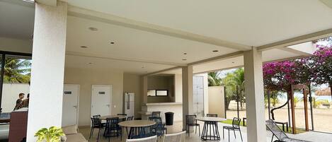 A covered outdoor area with seating and a pool.
