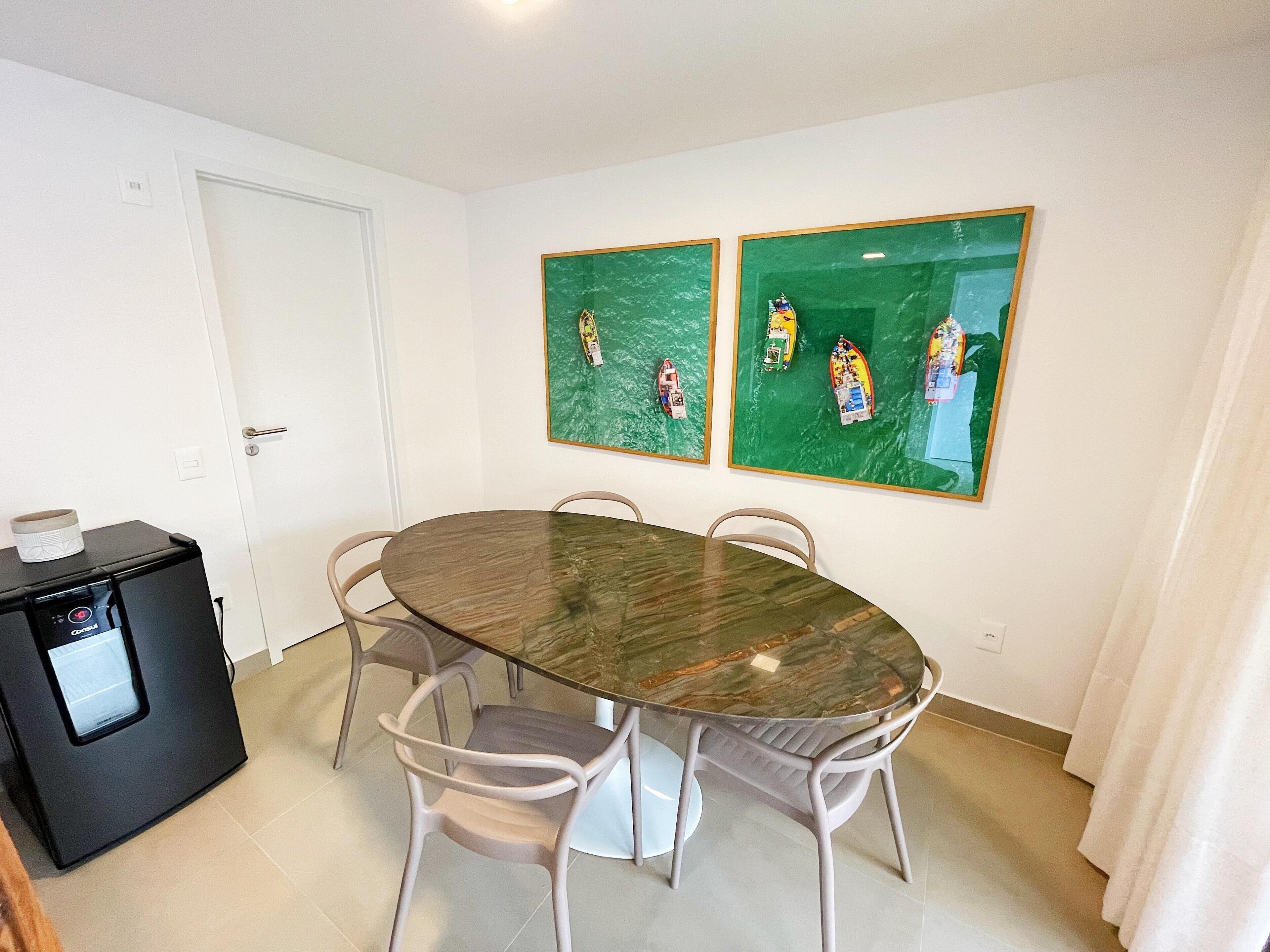 Un comedor con una mesa redonda, cuatro sillas y dos cuadros en la pared.