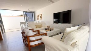 Een moderne woonkamer met een bank, stoelen, een salontafel en een flatscreen televisie.