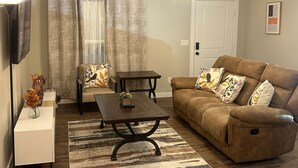Ein Wohnzimmer mit braunem Sofa, Couchtisch, Fernseher und Deckenventilator.