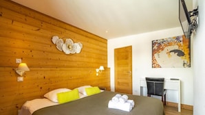 Una camera d'albergo con una testiera in legno, un letto con cuscini bianchi e gialli, una scrivania con una sedia e un quadro appeso al muro.