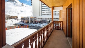 Un balcone con ringhiera in legno che si affaccia su una montagna innevata e una stazione sciistica.