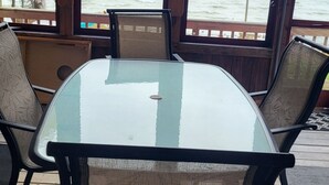 Mesa de vidrio con cuatro sillas en una habitación con ventanas amplias que dan a una extensión de agua.