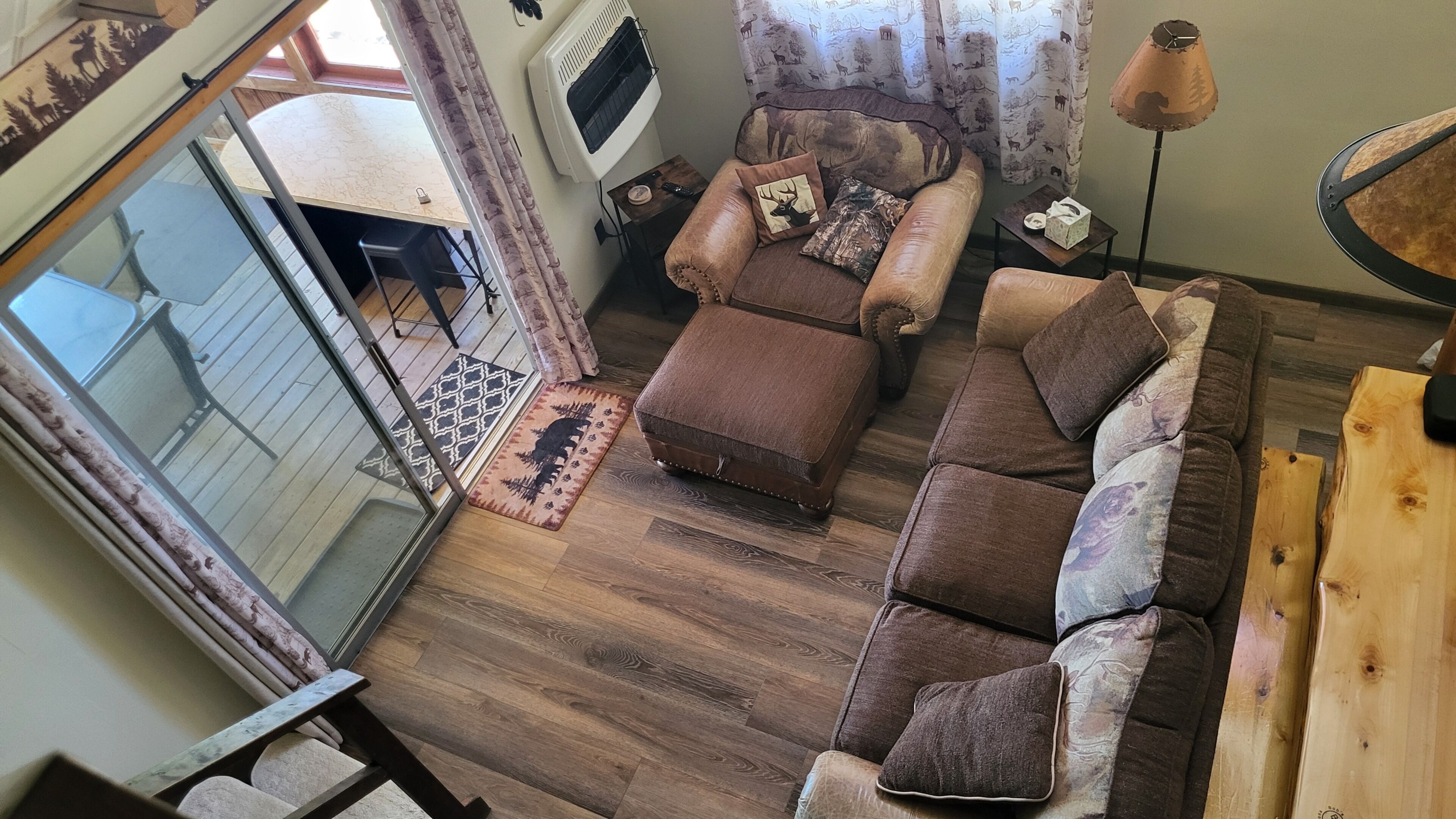 Un salon chaleureux avec un canapé en cuir marron, un pouf et un tapis à motifs.