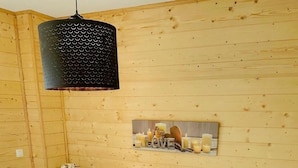 A wooden-paneled bedroom with a bed, a nightstand, a wall-mounted shelf with candles, and a hanging light fixture. - Chalet, 150m from resort center, view mountain, swimming pool, sauna, terrace, parking, tv (Agnières-en-Dévoluy)