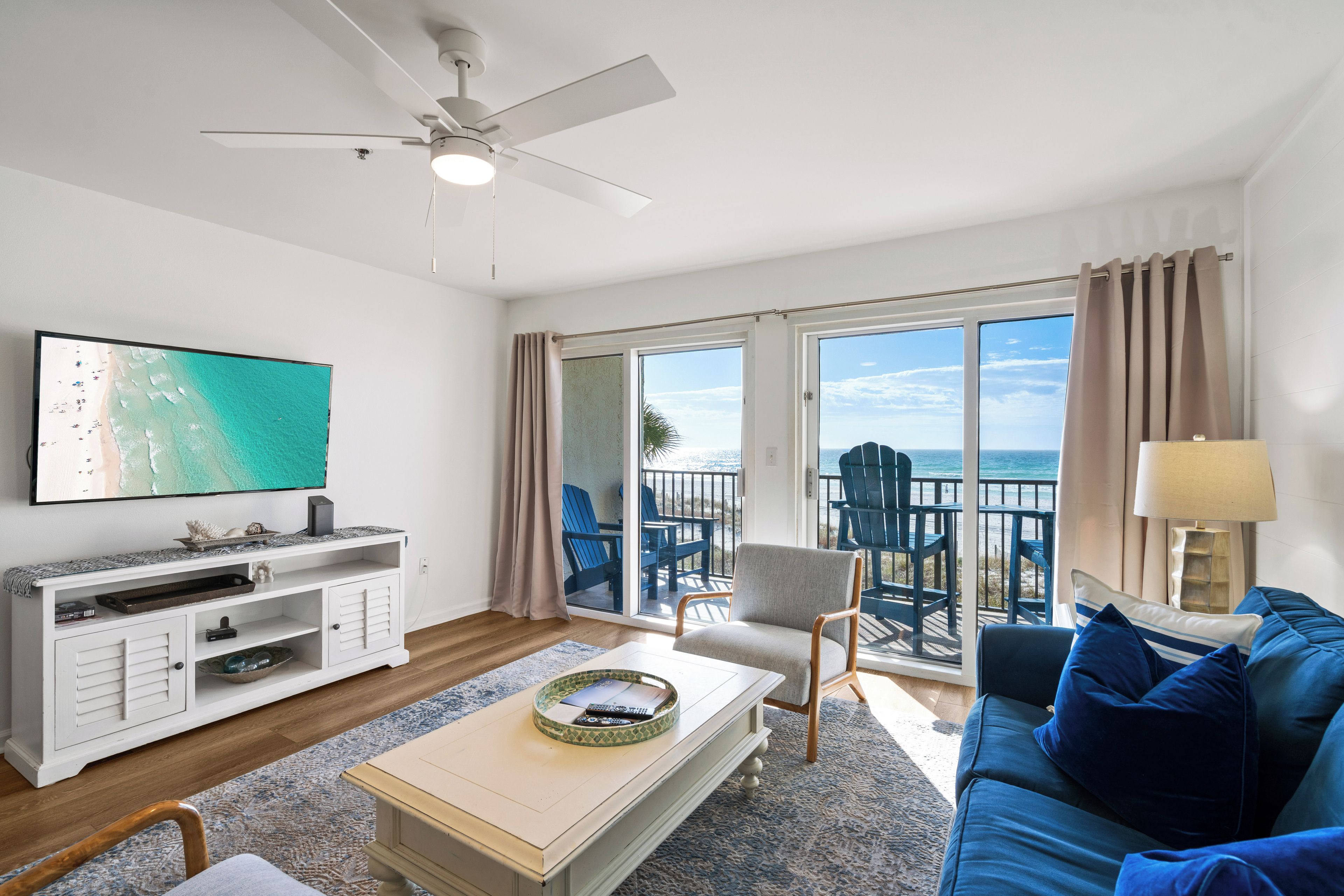 A living room with a television, sofa, coffee table, and a balcony with chairs.