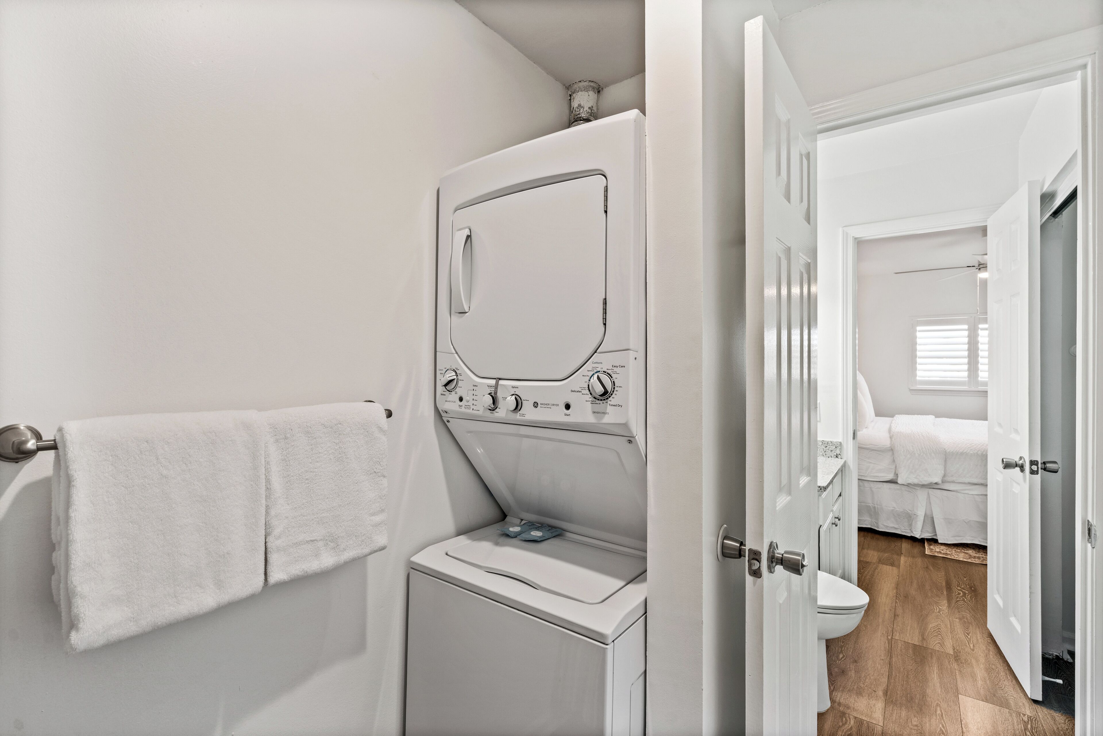 Een kleine, moderne badkamer met een ingebouwde wasmachine en droger, een toilet en een douchehoek.
