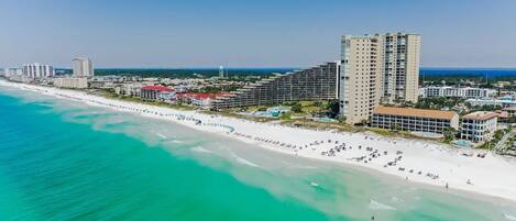 A coastal hotel with multiple high-rise buildings, a beach, and a clear blue sky.